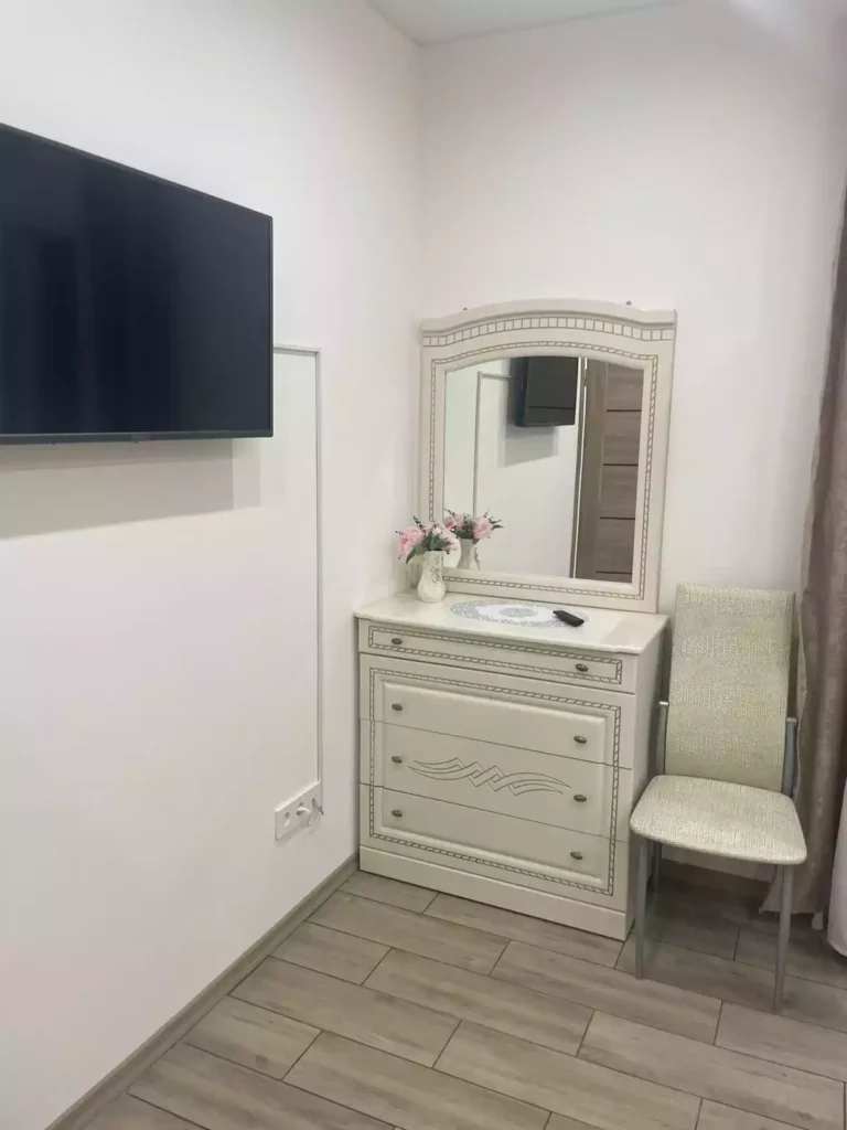 Телевизор на стене, стул, зеркало над комодом.